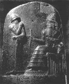 太陽神シャマシュより王権を象徴する葦のものさしと巻き尺に与えられるハンムラビ王が彫られている。
