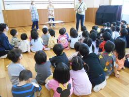 3～5歳児がホールに集まり、座って何が出てくるのか楽しみに待っています。