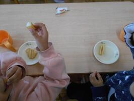 お皿にのったフライドポテトとそれをつまみ上げ口に運んでいるところです。