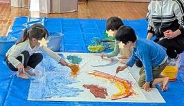 園児が大きな布に絵を描いているところ