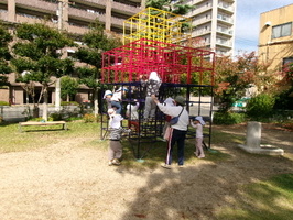 公園のジャングルジムで遊ぶ3歳児