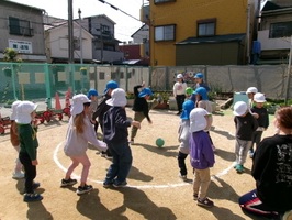 5歳児が3歳児にドッジボールのルールを教えながら、一緒に遊んでいます。