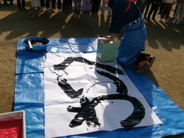 職員が大きな筆と紙で書初めをしました。平和への願いを込めて「平和」と書きました