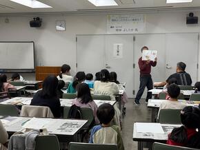 「うどんのうーやん」を読む岡田さんの写真