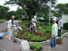 笑顔で花の植え付けをしている写真