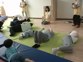 赤ちゃんの寝返りを体験する保護者の様子