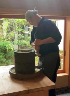 御嶽山の岩石でつくった石臼を挽く辻田さんの写真